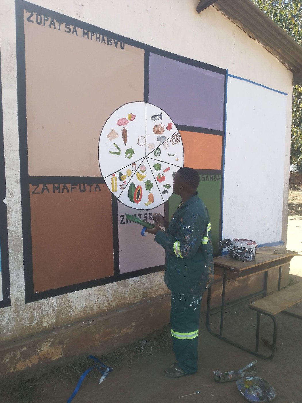 Artist painting a nutritional education mural on a community wall